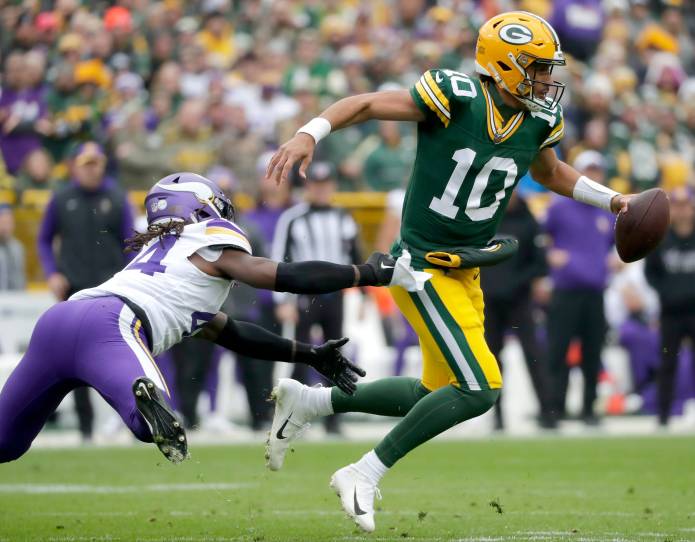 Green Bay Packers quarterback Jordan Love (10) is chased by Minnesota Vikings safety Josh Metellus (44) during their game at Lambeau Field on October 29, 2023. Minnesota defeated Green Bay 24-10.